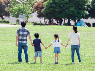 緑の芝生の公園で手をつなぐ家族
