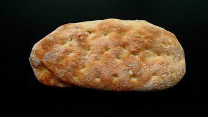 Loaf of Ciabatta bread on black wooden table