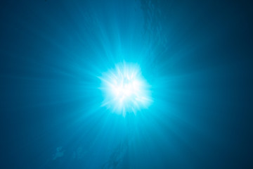Sunburst and light rays in the deep blue ocean water