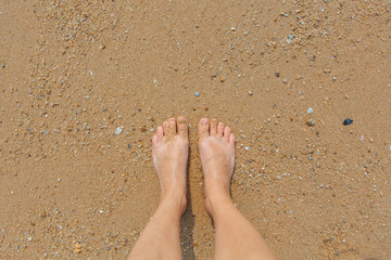 Bare female feet on the sea shore