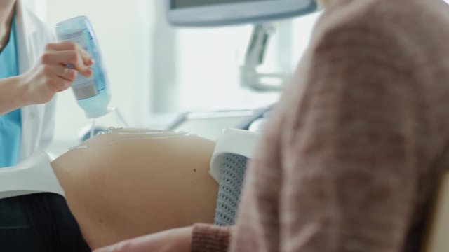 In the Hospital, Female Obstetrician Puts Gel on the Belly of a Pregnant Mother, Ready to do Ultrasound Screening. Shot on RED EPIC-W 8K Helium Cinema Camera.