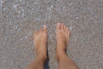 Bare female feet on the sea shore