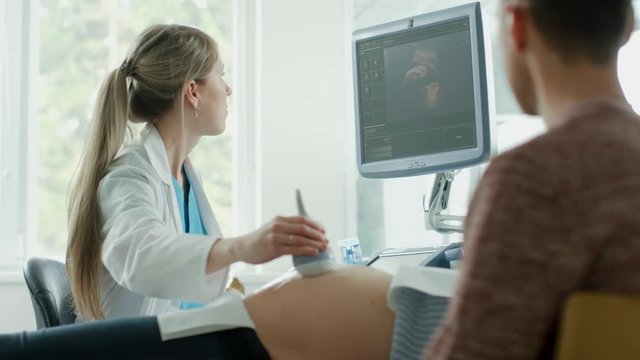 In the Hospital, Pregnant Woman Lying in Bed, Obstetrician Pushes Buttons on a Control Panel and Starts Ultrasound / Sonogram Procedure. Shot on RED EPIC-W 8K Helium Cinema Camera.