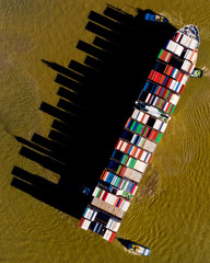 Aerial view of a large freighter projecting a cityscape-like shadow onto the water