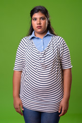 Obraz premium Young overweight beautiful Indian businesswoman against green background