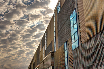 Modern building exterior with sky and clouds reflecting in the windows