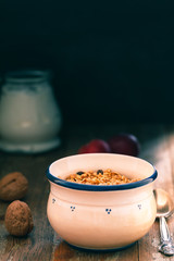 Bowl with Granola or Muesli and a jar of milk or plain yogurt with a spoon on a vintage wood background. Healthy breakfast composition