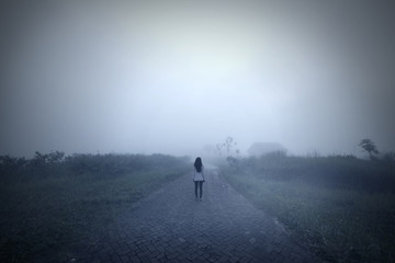 Young woman standing alone in the misty morning