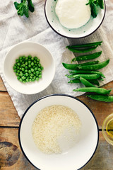 Set ingredients cooking vegetarian risotto green peas mint goat cheese wooden rustic table top view Healthy food concept