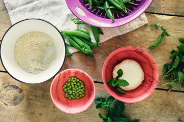 Raw ingredients cooking vegetable risotto green peas mint goat cheese wooden rustic table top view Healthy food concept
