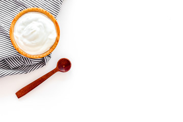 Healthy product, healthy meal. Greek yogurt in brown bowl near spoon on blue tablecloth, white background top view copy space