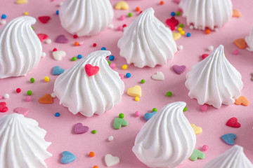 twisted meringues with confectionary decorations pink background.