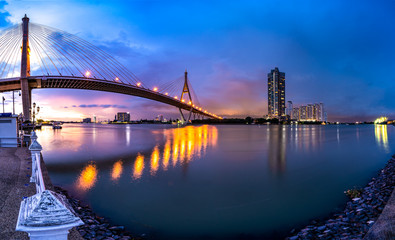 Bhumibol Bridge, the Industrial Ring Road Bridge with skyscraper in the night scene after sunset. Twilight sky and light reflection on smooth water, Thailand