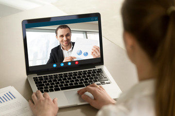 Fototapeta na wymiar Happy businessman showing positive financial report to remote colleague via video conference call. Project manager proudly shows successful results over webcam application. Closeup view over shoulder.