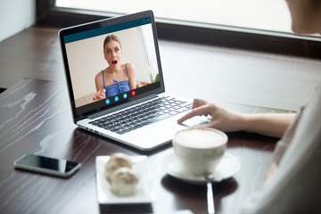 Two girlfriends chatting on laptop via video call application. Girl on screen has surprised expression. Friend tells personal secret, chat via webcam, virtual communication. Close up, focus on screen.