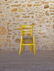 yellow chair on stone wall background