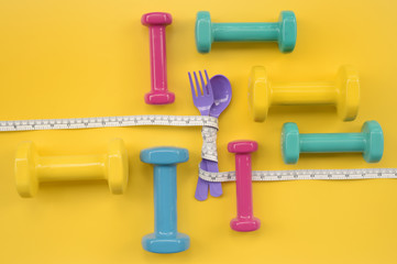 close up of spoon in tape measure with dumbbell for background