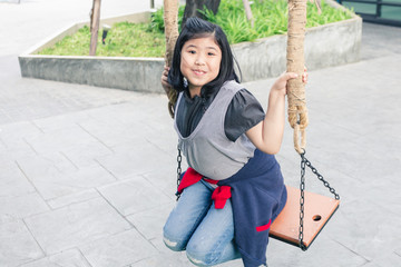 Asian girl sitting on chain swing wood