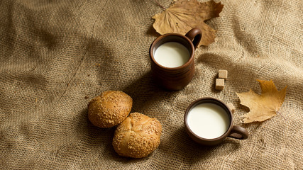Obraz na płótnie Canvas bread, brown sugar, maple leaf and two cups of milk