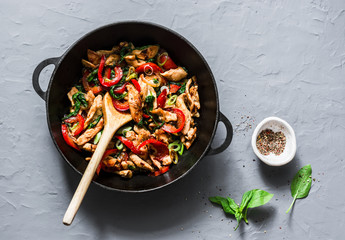 Teriyaki chicken, bell peppers, onions and spinach stir fry in a pan on a gray background, top view