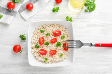 Plate with delicious brown rice and vegetables on table
