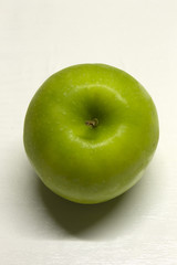 Green Apple isolated on a White textured background with a dark shadow