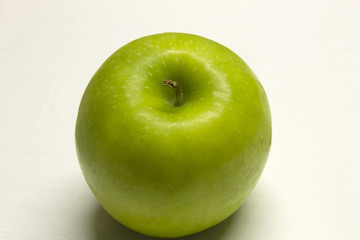 Green Apple isolated on a White textured background with a dark shadow