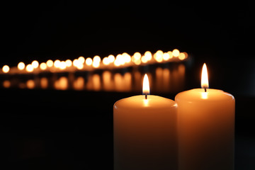 Small wax candles burning in darkness, closeup