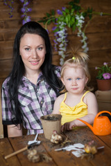 woman is teaching her daughter to plant flowers