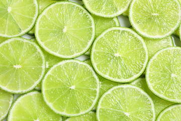 Fototapeta na wymiar Fresh sliced ripe limes as background, top view