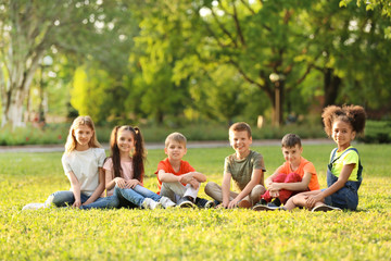 Fototapeta premium Cute little children sitting on grass outdoors on sunny day