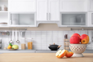 Ripe apples and blurred view of kitchen interior on background