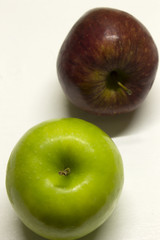 Green and Red Apples isolated on a White textured background with a dark shadow