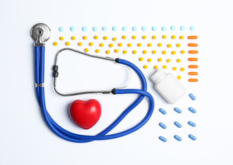 Flat lay composition with medical equipment and pills on light background