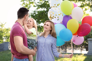 Happy family with colorful balloons outdoors on sunny day