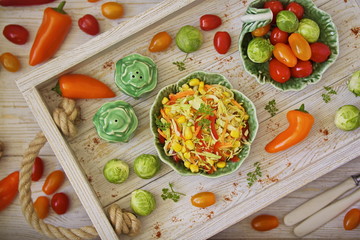 Young cabbage salad with pepper and corn in a beautiful salad bowl in a white vegetable box