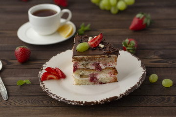 Delicious cake with strawberries, grapes, chocolate, tea with lemon
