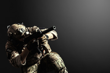 Special forces soldier with rifle on dark background