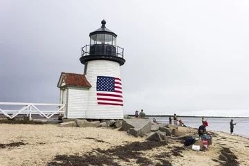 Papier Peint photo Phare Nantucket, Massachusetts. Brant Point Light, a lighthouse located on the harbor of Nantucket Island, with several people fishing and an American flag