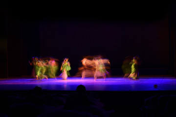 Obraz premium A group of people dancing on stage against dark black
