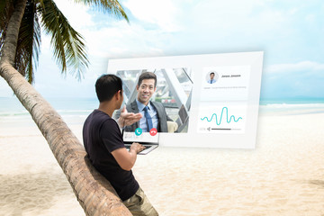 Young man having remote video conference call with manager at the beach