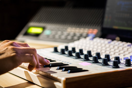 musician hands playing midi keyboard in sound studio, recording concept