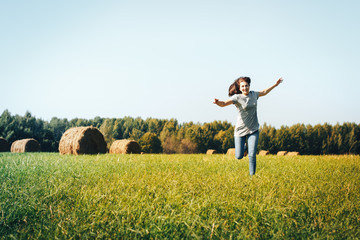 Naklejka na ściany i meble Girl in an autumn field with hay stack