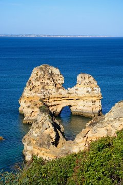 View of rocky coastline and the sea with a natural arch, Praia da Dona Ana, Lagos, Portugal.