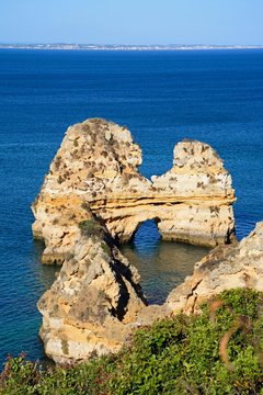 Elevated view of the coastline with a natural arch in the ocean, Praia da Dona Ana, Lagos, Portugal.
