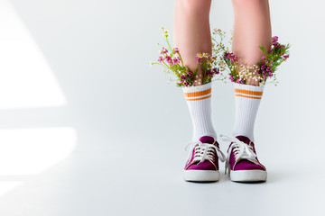 cropped shot of girl with fresh flowers in socks on grey