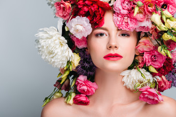 portrait of gorgeous naked woman with beautiful flowers on head looking at camera isolated on grey
