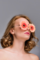 low angle view of naked girl wearing glasses with flowers isolated on grey