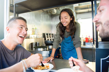 Young men enjoy talking and eating pasta at food truck