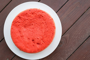 red biscuit standing on a white plate on a wooden background. large plan, top view